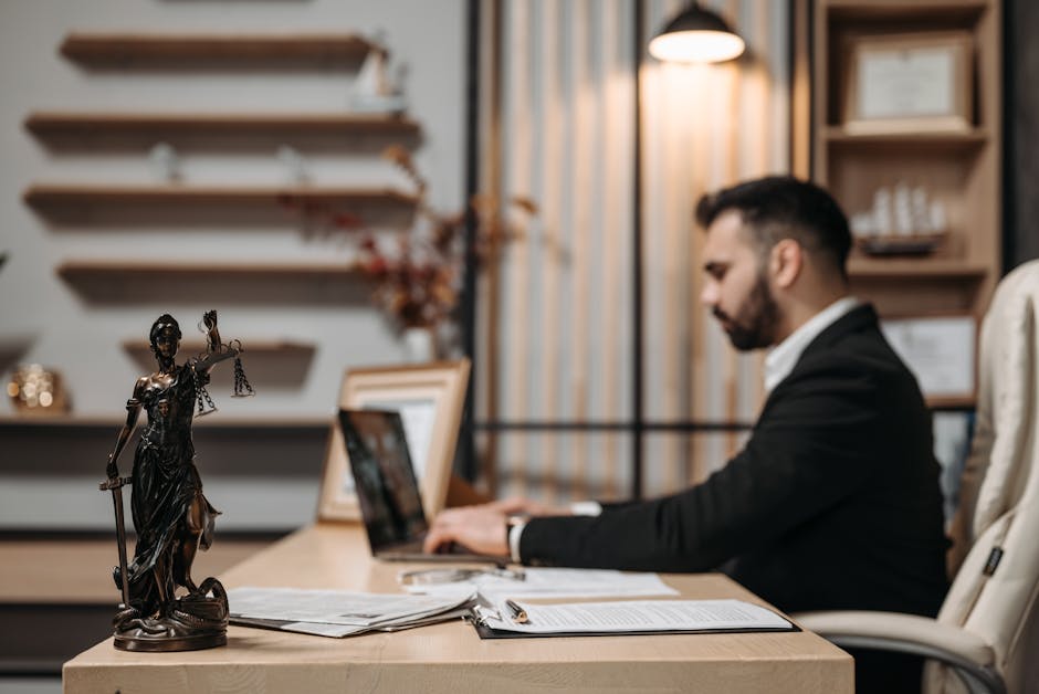 Lawyer working diligently on a laptop in a modern office, Lady Justice statute present